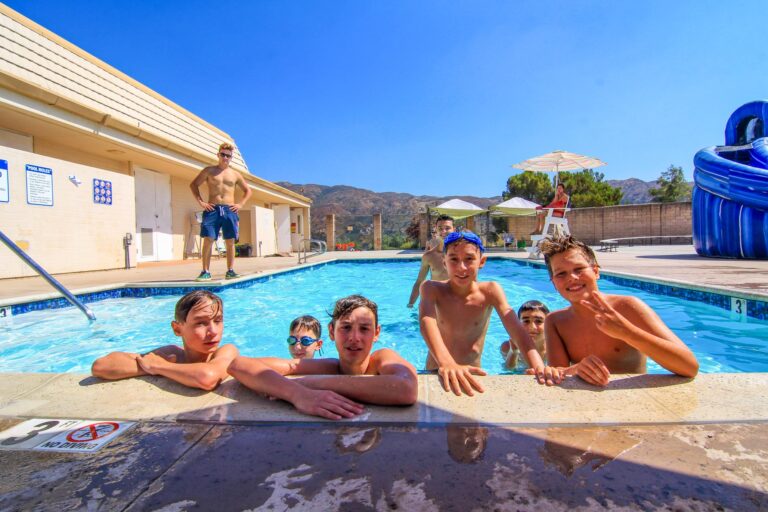 boys hanging on edge of a pool.