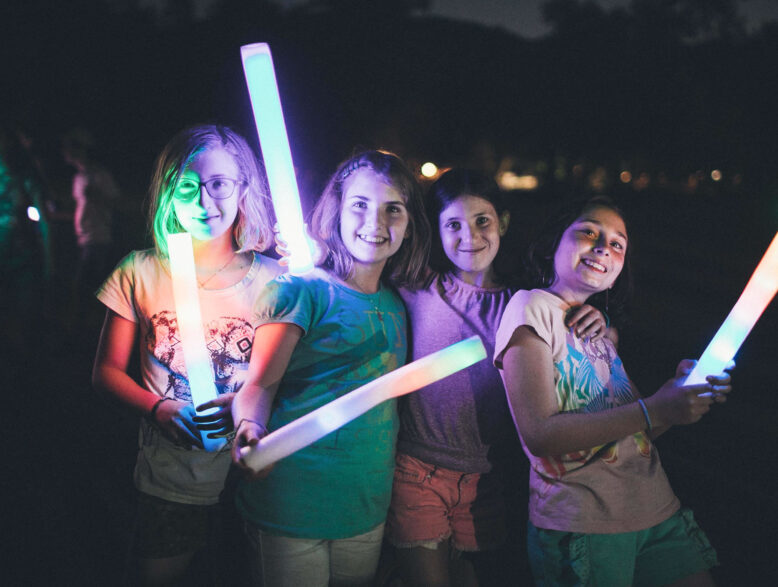 group of girls holding illuminated sticks at night.