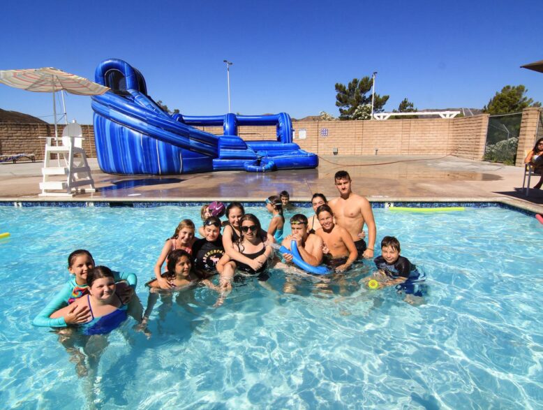 group of adults and kids in an outdoor swimming pool.