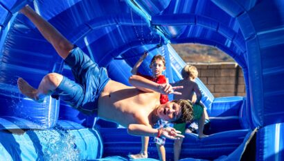 boy jumping sideways while going down a water slide,
