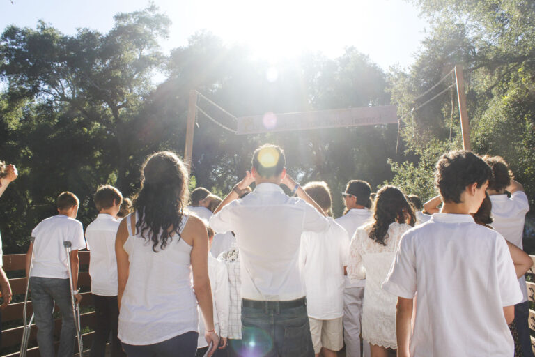 kids in white shirts facing away towards the sun outside with a lens flare.