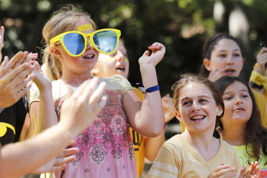 girl wearing oversized yellow glasses surrounded by other kids.
