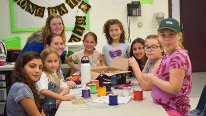 group of girls working on crafts at a table.