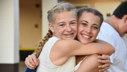 two girls smiling and hugging eachother.