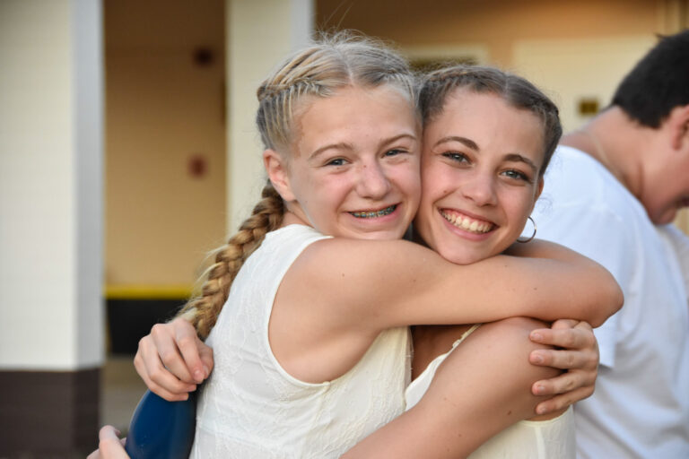 two girls smiling and hugging eachother.