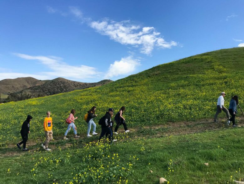 teens walking up the side of a grassy hill.