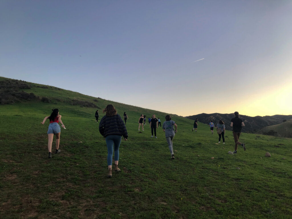 teens running up a hill at dusk.
