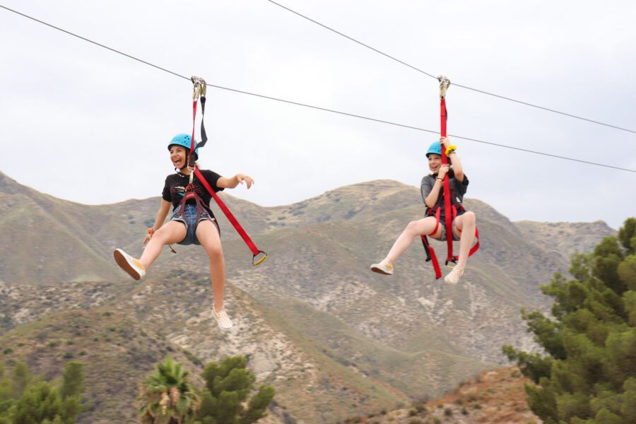 two girls laughing while riding a zip line.