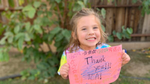 girl holding thank you sign.