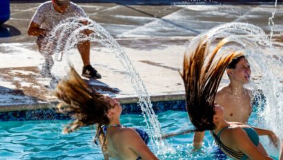 two teen girls flipping water into the air with their hair in a pool.