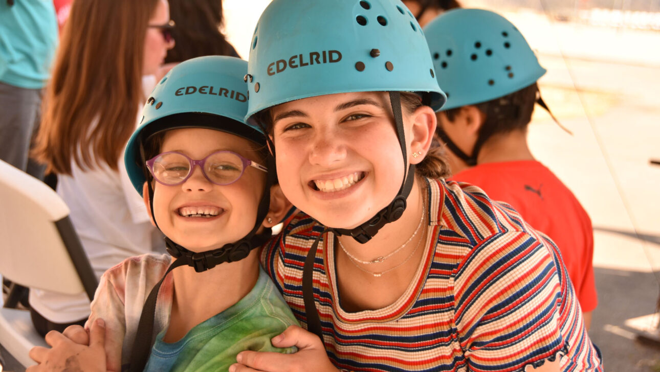 two girls in blue helmets smiling.