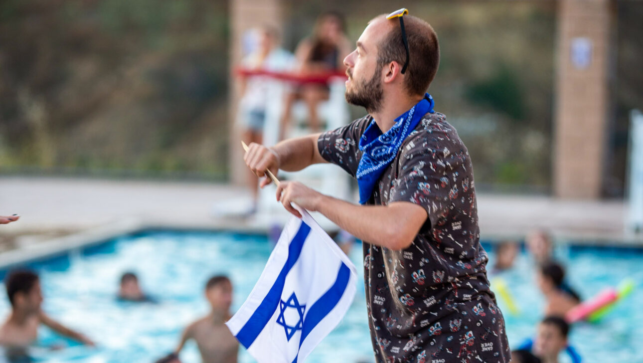 man waving an israeli flag next to a swimming pool.