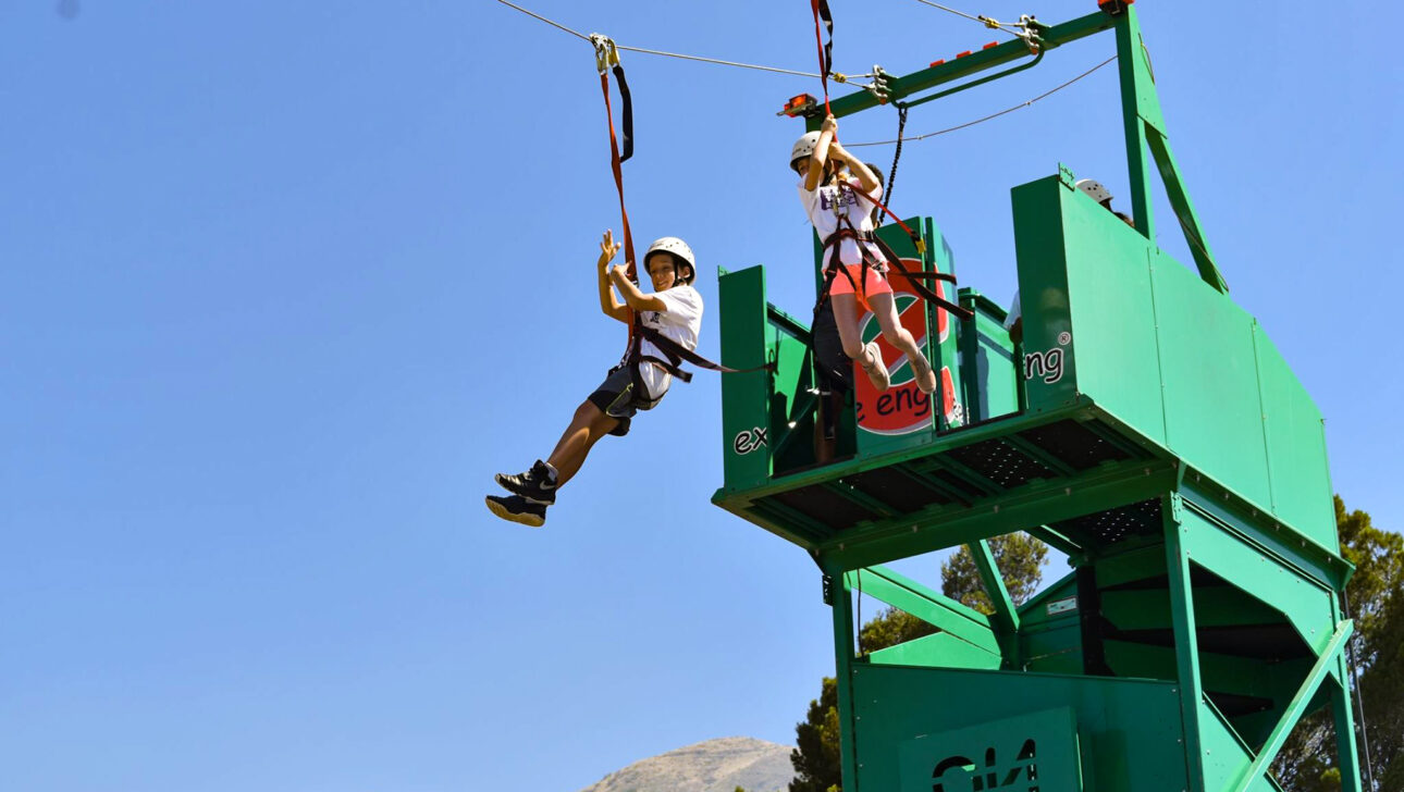two boys jumping off a zip line tower.